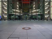 a very big square with some stairs and windows at night time with a fire hydrant sitting in front of it