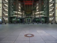 a very big square with some stairs and windows at night time with a fire hydrant sitting in front of it