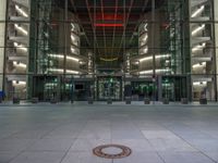 a very big square with some stairs and windows at night time with a fire hydrant sitting in front of it