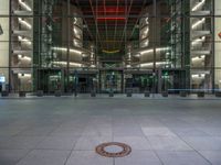 a very big square with some stairs and windows at night time with a fire hydrant sitting in front of it