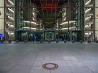 a very big square with some stairs and windows at night time with a fire hydrant sitting in front of it