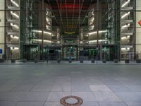 a very big square with some stairs and windows at night time with a fire hydrant sitting in front of it