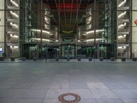 a very big square with some stairs and windows at night time with a fire hydrant sitting in front of it