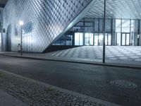 the empty walkway next to a glass structure on a building street in the city at night