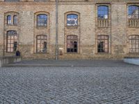 an old brick building with windows and a parking area for bicycles to cycle around on