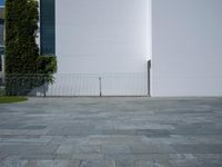a concrete floor with large tiles outside the building and a fence surrounding it in front of an iron gate