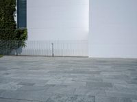 a concrete floor with large tiles outside the building and a fence surrounding it in front of an iron gate