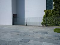 a concrete floor with large tiles outside the building and a fence surrounding it in front of an iron gate
