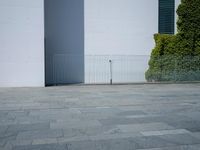 a concrete floor with large tiles outside the building and a fence surrounding it in front of an iron gate