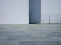 a concrete floor with large tiles outside the building and a fence surrounding it in front of an iron gate