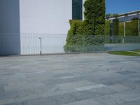 a concrete floor with large tiles outside the building and a fence surrounding it in front of an iron gate