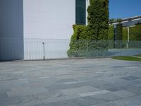 a concrete floor with large tiles outside the building and a fence surrounding it in front of an iron gate
