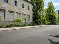 a sidewalk near buildings that are not in use anymore?, with trees on either side