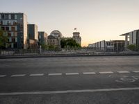 an empty city street and bridge crossing over a river at dusk with buildings in the background