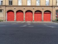 red firehouse doors line an empty road near an apartment building with arched arch windows