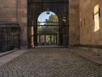 an arch is opening the entry to a building with stone flooring and two large arched windows