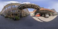 this is a panoramic view of the street of a city with buildings and a bus passing by