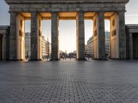 a person sits on top of a stone floor next to a street with pillars in the background