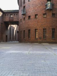 an empty courtyard and brick buildings with cobblestones on a cloudy day from the sun