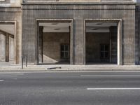 a stop sign on the sidewalk next to a big building with many windows and a parking space in front
