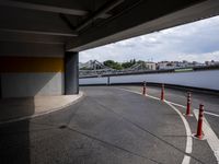 a view of an empty street underneath a bridge with a long orange caution line through the distance