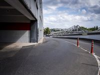 a view of an empty street underneath a bridge with a long orange caution line through the distance