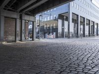 the man rides a skateboard down a cobblestone street next to tall buildings