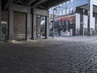 the man rides a skateboard down a cobblestone street next to tall buildings