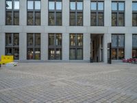 a courtyard with a building on the other side and a large white building with many windows