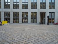 a courtyard with a building on the other side and a large white building with many windows