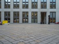 a courtyard with a building on the other side and a large white building with many windows