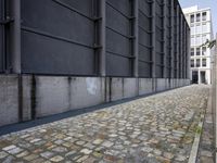 an empty brick sidewalk next to a building with some windows and doors in the back