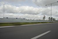 a photo taken of an empty road with a car on it and clouds above the road