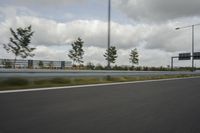 a photo taken of an empty road with a car on it and clouds above the road