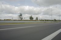 a photo taken of an empty road with a car on it and clouds above the road