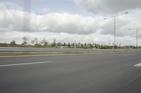 a photo taken of an empty road with a car on it and clouds above the road