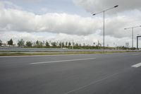 a photo taken of an empty road with a car on it and clouds above the road