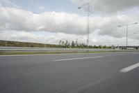 a photo taken of an empty road with a car on it and clouds above the road