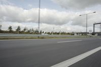 a photo taken of an empty road with a car on it and clouds above the road