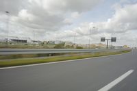 a photo taken of an empty road with a car on it and clouds above the road