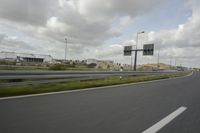 a photo taken of an empty road with a car on it and clouds above the road