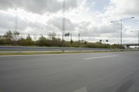 a photo taken of an empty road with a car on it and clouds above the road