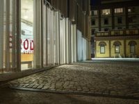 the street is empty and empty outside of a large building at night with the shutter open