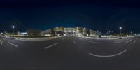 a nighttime photo shows an empty street near buildings and lights while a blurry car moves by