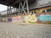 a long brick sidewalk with grafitued graffiti on it's side and buildings behind