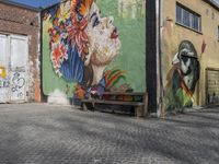 mural of a woman with flowered headdress on a brick building along a cobblestone driveway