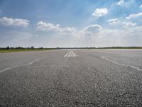 the sky is a blue and cloudy sky behind the clouds above an airport runway with white lines on it