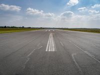 the sky is a blue and cloudy sky behind the clouds above an airport runway with white lines on it