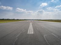 the sky is a blue and cloudy sky behind the clouds above an airport runway with white lines on it