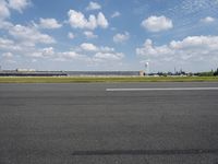 a jet airplane is on the runway in an airport area with a sky background and some clouds